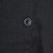 A close up of a black button on a black Chef Revival chef coat.