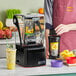 A man using a Blendtec Stealth 895 Nitro blender to make a yellow smoothie with pineapple.