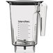 A clear Blendtec blender jar with a clear lid and a handle.