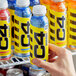 A person's hand holding a C4 Energy Icy Blue Razz energy drink bottle with a yellow and black label and a blue cap.