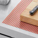 Red plastic mesh shelf liner with a knife on a cutting board.