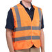 A man wearing a Cordova orange high visibility safety vest with reflective stripes.