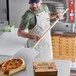 A man using a Choice aluminum pizza peel to put a pizza in a box.