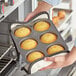 A person using a Choice jumbo muffin pan to bake muffins.