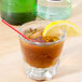 A Libbey rocks glass with a brown liquid, a straw, and a lemon slice.