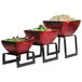 A Vollrath black stainless steel square riser set with three bowls of food on it.
