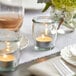A table set with Acopa glass votive candle jars filled with lit candles.