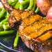A Fineline Savvi Serve clear plastic plate with grilled pork chops and green beans.