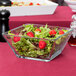 A close-up of a Libbey square glass bowl filled with salad and strawberries.