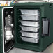 A green Cambro Ultra Pan Carrier with food trays inside.