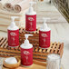 A group of Noble Eco Novo Natura hotel amenity bottles with red and white labels and white lids on a wooden tray.