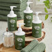 A wooden tray holding green Noble Eco Novo Terra hotel toiletry bottles and a green towel.