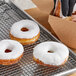 A tray of Pillsbury Tender Taste donuts with white frosting on a metal rack.