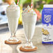 Two glasses of Island Oasis vanilla milkshakes with sprinkles and straws.