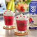Two glasses of Island Oasis Blueberry Pomegranate Frozen Beverage with whipped cream and berries.