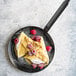 A de Buyer carbon steel crepe pan with a crepe topped with raspberries.
