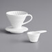 A white Hario V60 coffee dripper and a white coffee cup on a gray surface.