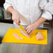 A person cutting chicken on a Tablecraft flexible cutting board.