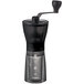 A Hario coffee grinder with a black handle and clear glass.