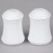 Two Tuxton bright white china salt and pepper shakers on a gray surface.
