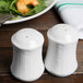 A Tuxton bright white china salt and pepper shaker set on a table.