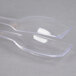 A clear plastic container holding clear plastic squeeze tongs with a spoon on top.