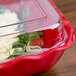 A clear lid on a red Cambro Deli Crock full of food.