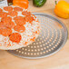 A pizza on an American Metalcraft Super Perforated Pizza Pan.