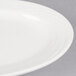 A close-up of a CAC Garden State bone white oval porcelain platter with a wavy rim.