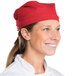 A smiling chef wearing a red Intedge chef neckerchief on a counter in a professional kitchen.