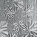 A close up of a silver surface with a drawing of leaves on it.