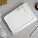 A white cake on a silver Enjay quarter sheet cake board with frosting.