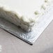 A white cake with frosting on an Enjay silver cake board.