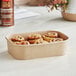 A brown rectangular Kraft paper take-out container with cinnamon rolls inside.