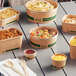 A group of EcoChoice compostable PLA take-out food containers on a table full of food.