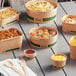 A group of EcoChoice compostable take-out containers with lids on a table of food.