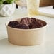 A Choice kraft paper bowl filled with chocolate cookies on a table.