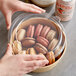 A hand placing a Choice PET take-out lid on a container of cookies.