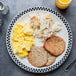 A Homer Laughlin creamy white china plate with eggs, sausage, and hash browns on it.