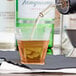 A Fineline clear plastic shot glass being filled with brown liquid.