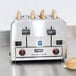 A Waring commercial toaster with four slices of bread in it on a kitchen counter.