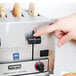 A person pressing a button on a Waring commercial toaster.