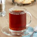 A glass mug of Bigelow Earl Grey tea on a saucer.