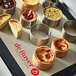 A metal circular tart ring with perforations on a tray of pastries.