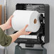 A person holding a roll of Tork Advanced white paper towels.