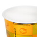A Huhtamaki paper soup cup with a yellow and orange design.