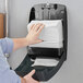 A person's hand pulling a stack of Tork Advanced Xpress white multi-fold paper towels from a dispenser.