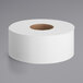 A Tork jumbo toilet paper roll on a gray surface with a hole in it.