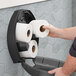 A man putting a Tork Universal toilet paper roll into a holder.