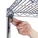 A hand holding a metal shelf with rubber casters.